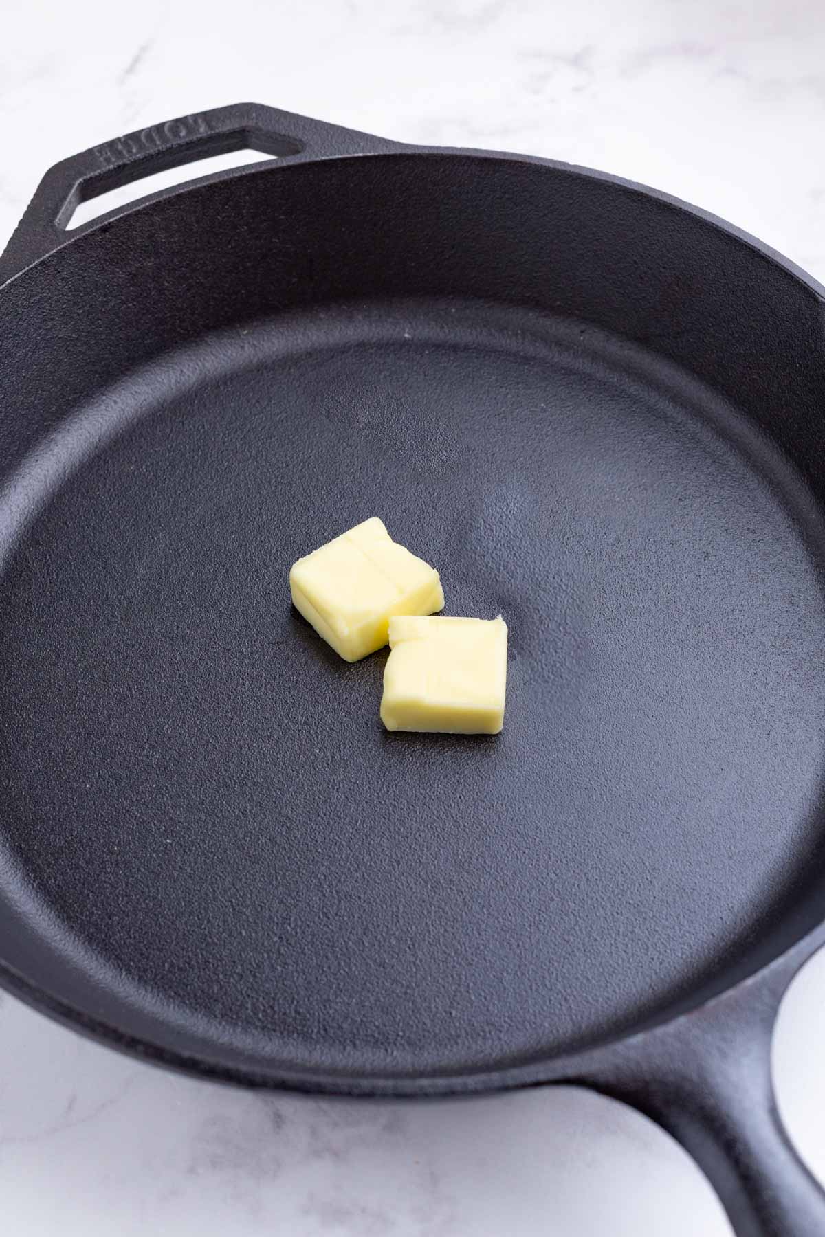 Butter is added to a cast iron skillet.