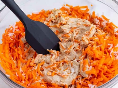 A spatula folds in the carrots and coconut.