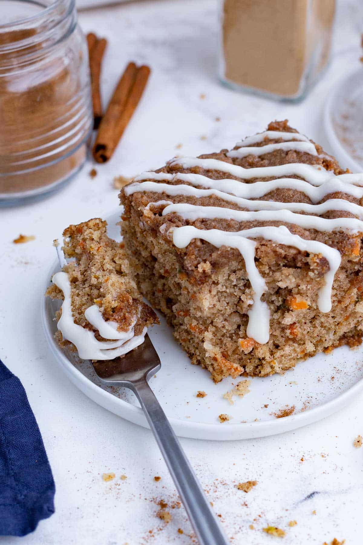 A fork digs into a slice of carrot coffee cake on a plate.
