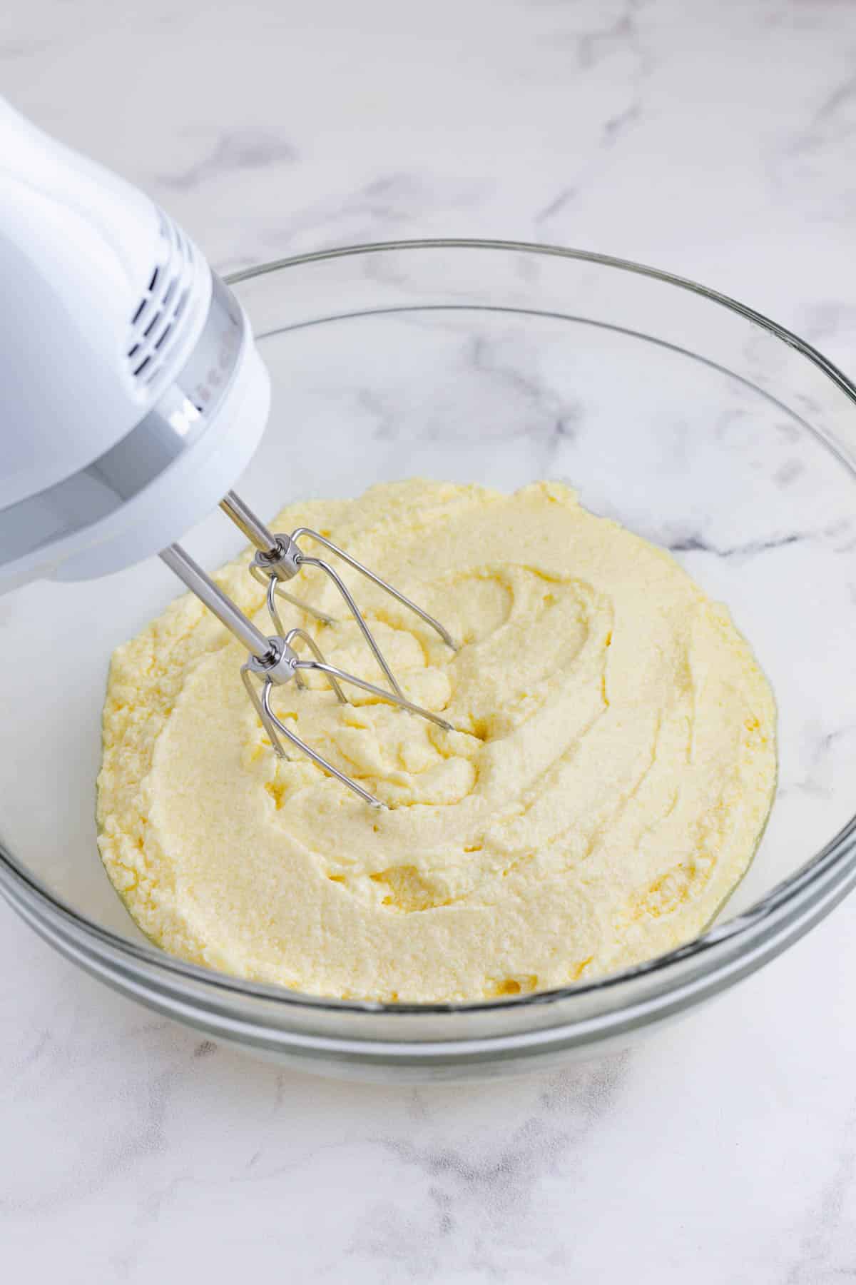 A handmixer beats together the eggs and butter mixture.