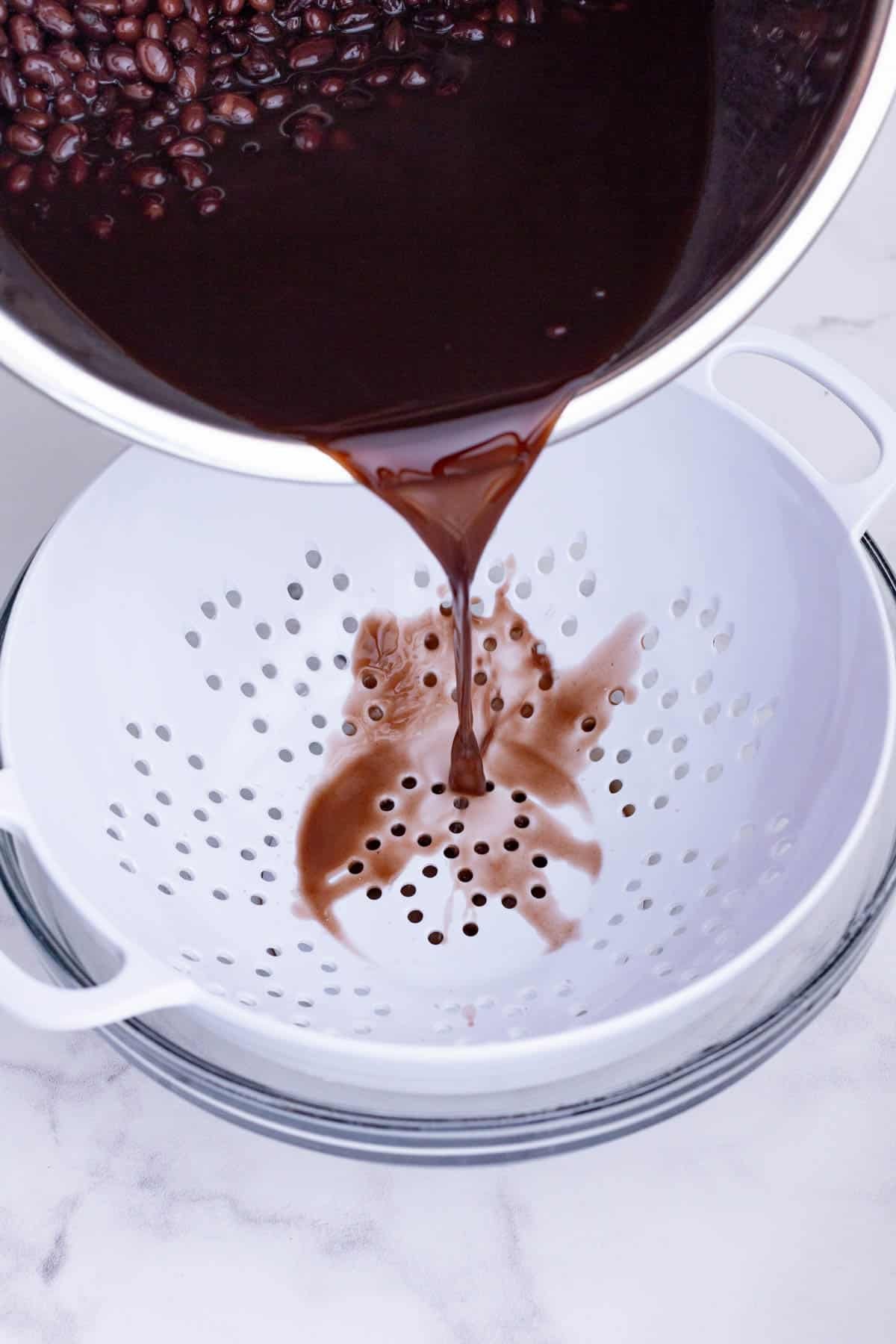 Cooked black beans are drained in a colander.