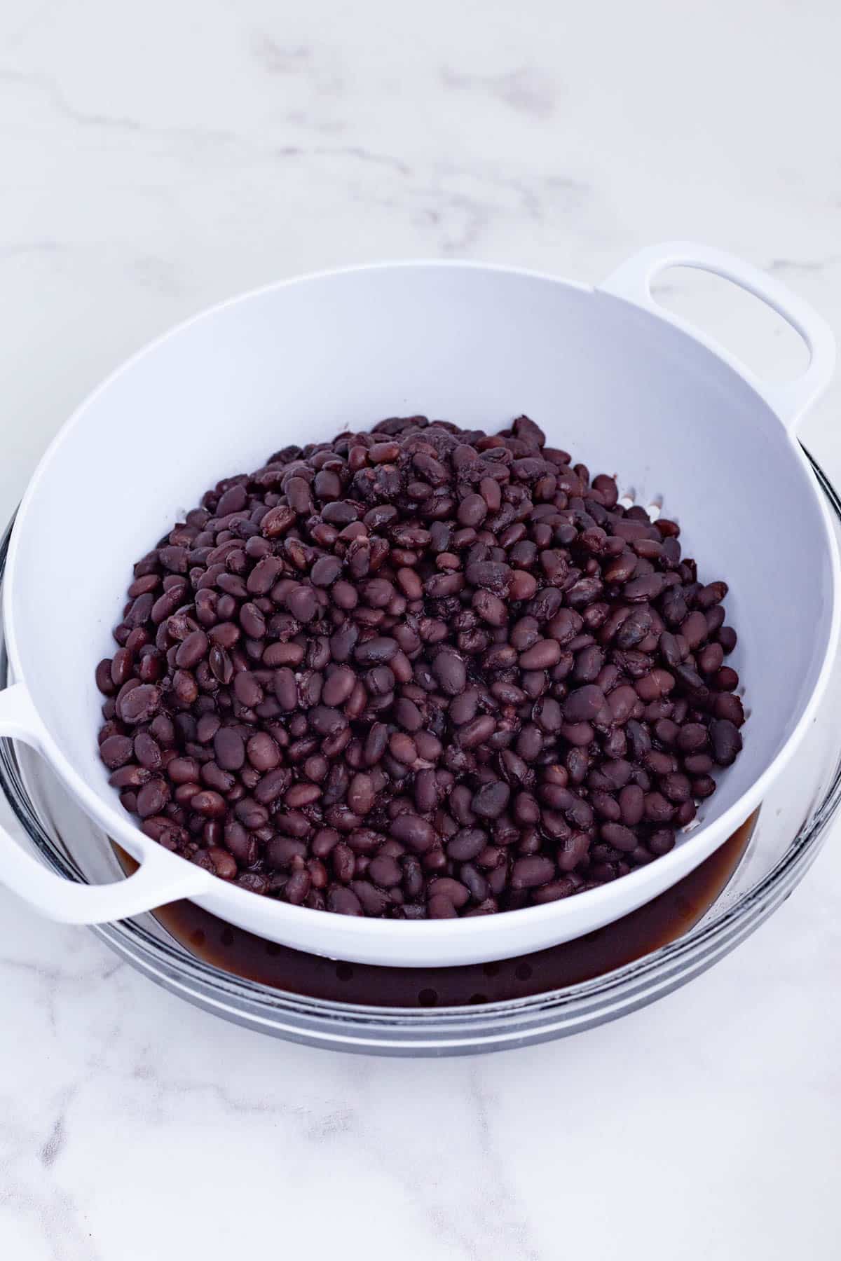 Cooked black beans are drained in a colander.