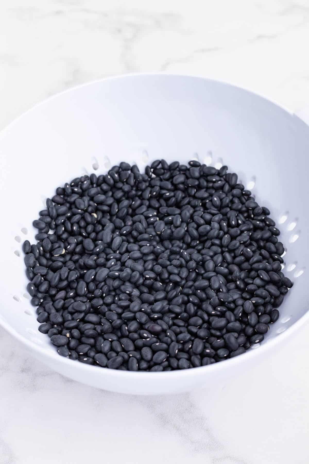 Dry beans are rinsed in a colander.