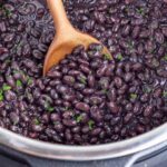 A spoon scoops cooked black beans out of an Instant Pot.