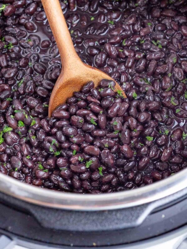 A spoon scoops cooked black beans out of an Instant Pot.