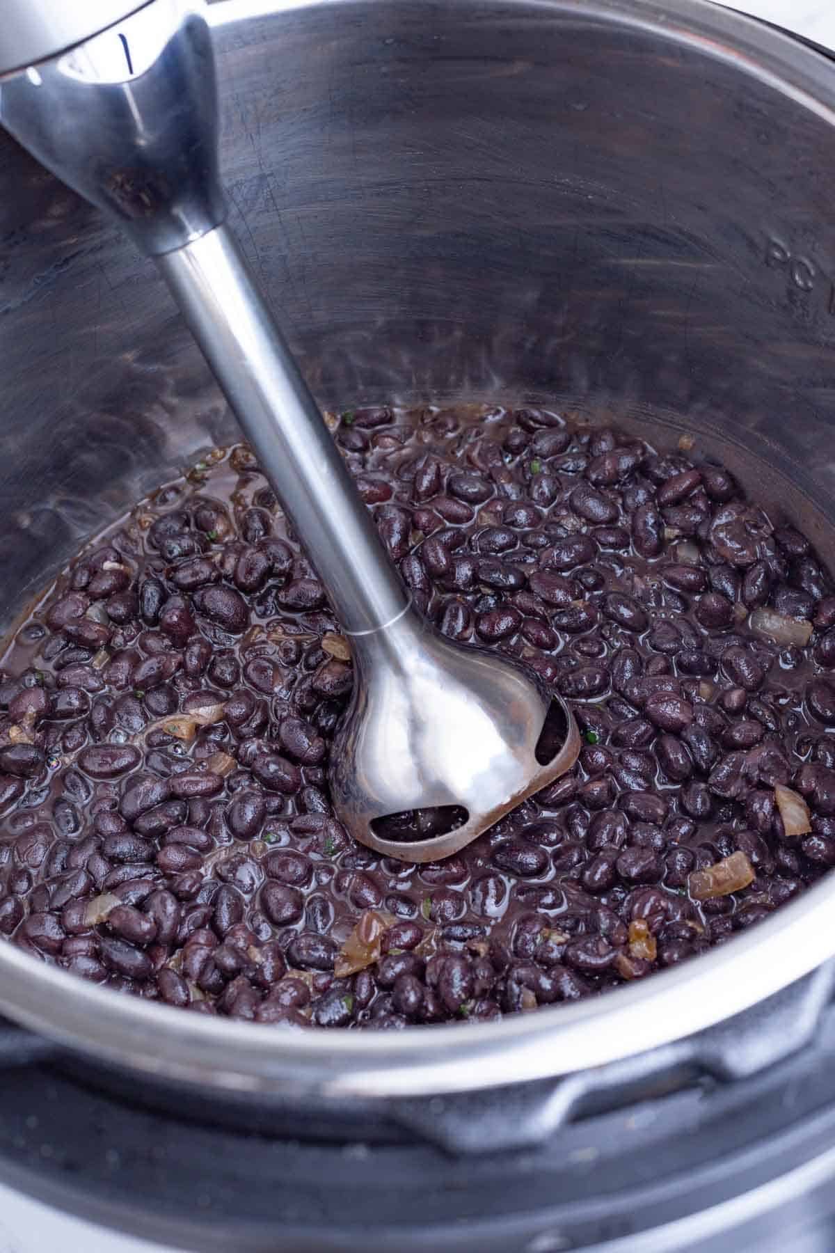 An immersion blender is used to liquify the beans.