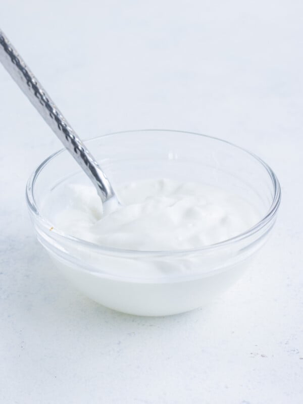 Glass bowl with sour cream and a spoon in it.