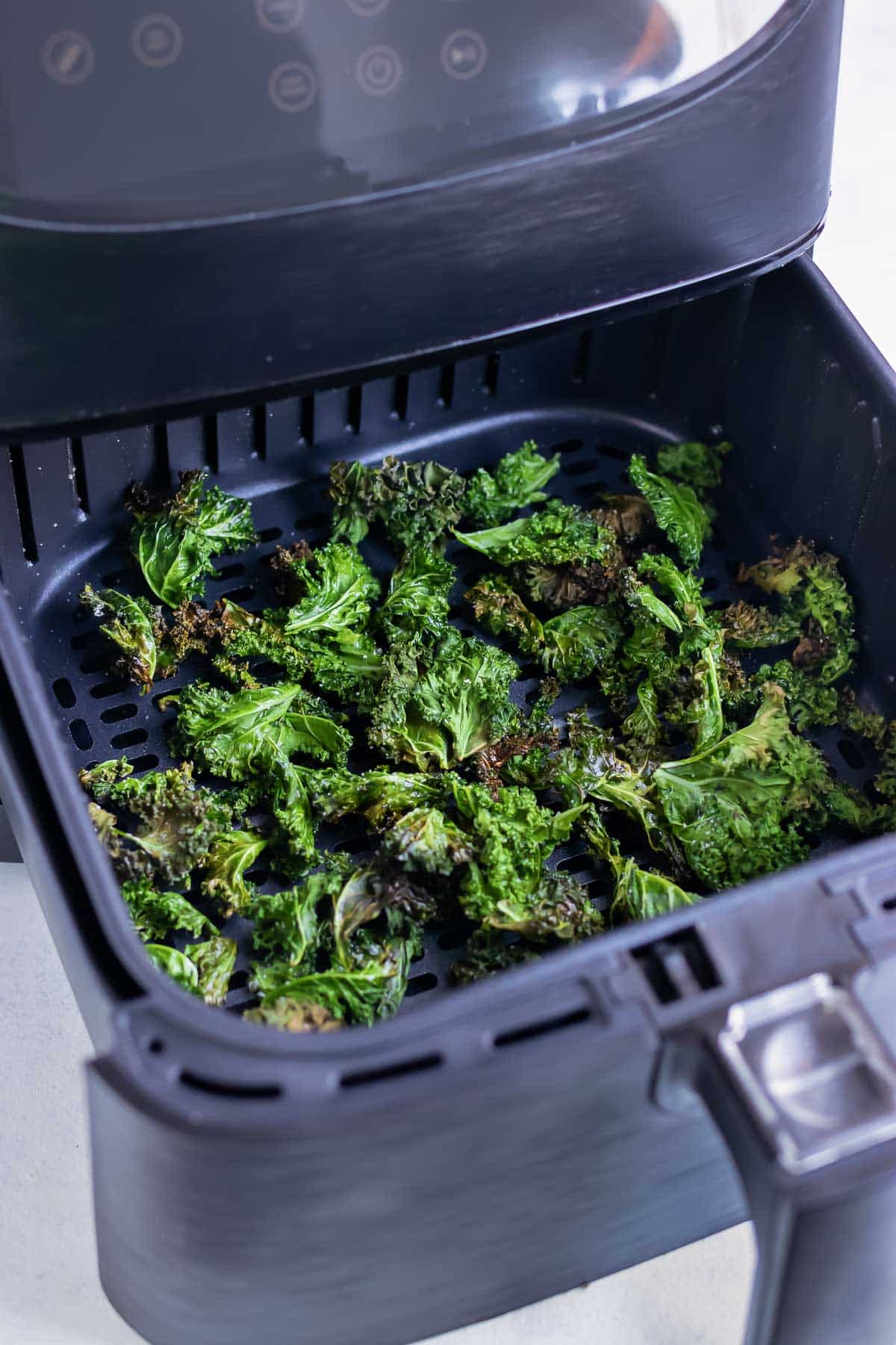The healthy kale chips are cooked in an air fryer until crunchy.