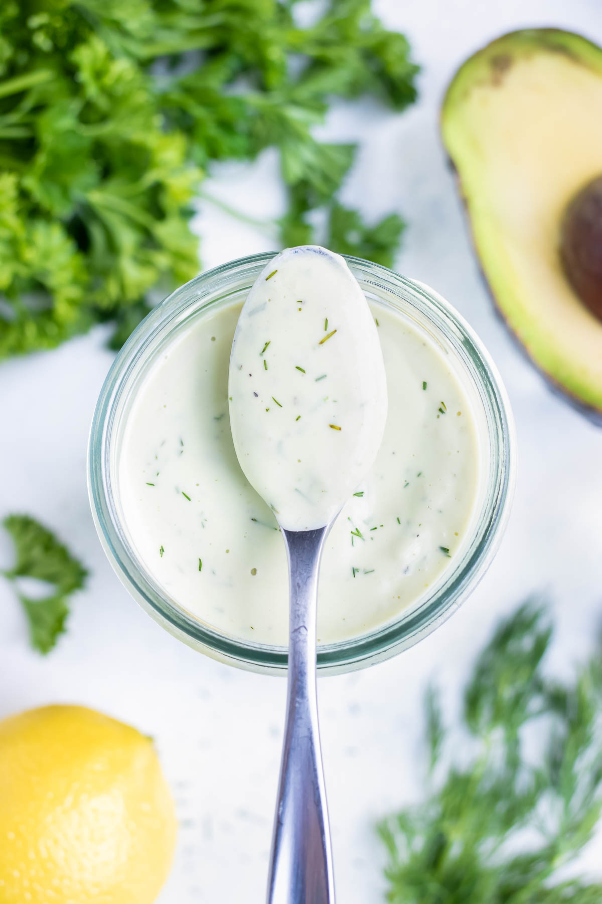 A jar of creamy avocado ranch dressing is set on the counter.