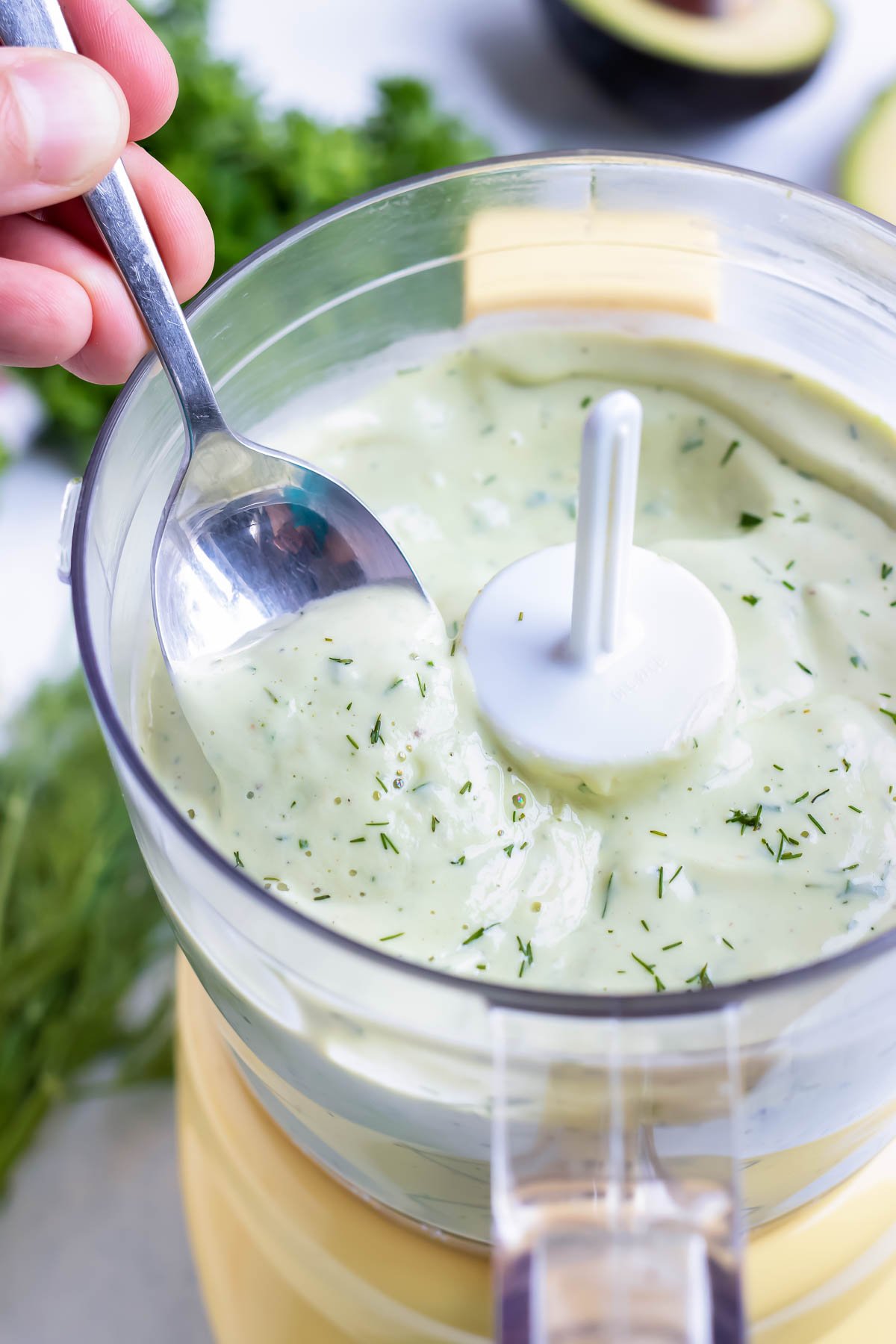 Homemade avocado dip is scooped up with a metal spoon.