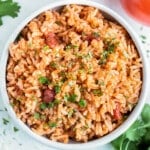 A white bowl is full of Instant Pot Mexican Rice made with salsa, white rice, and cilantro.