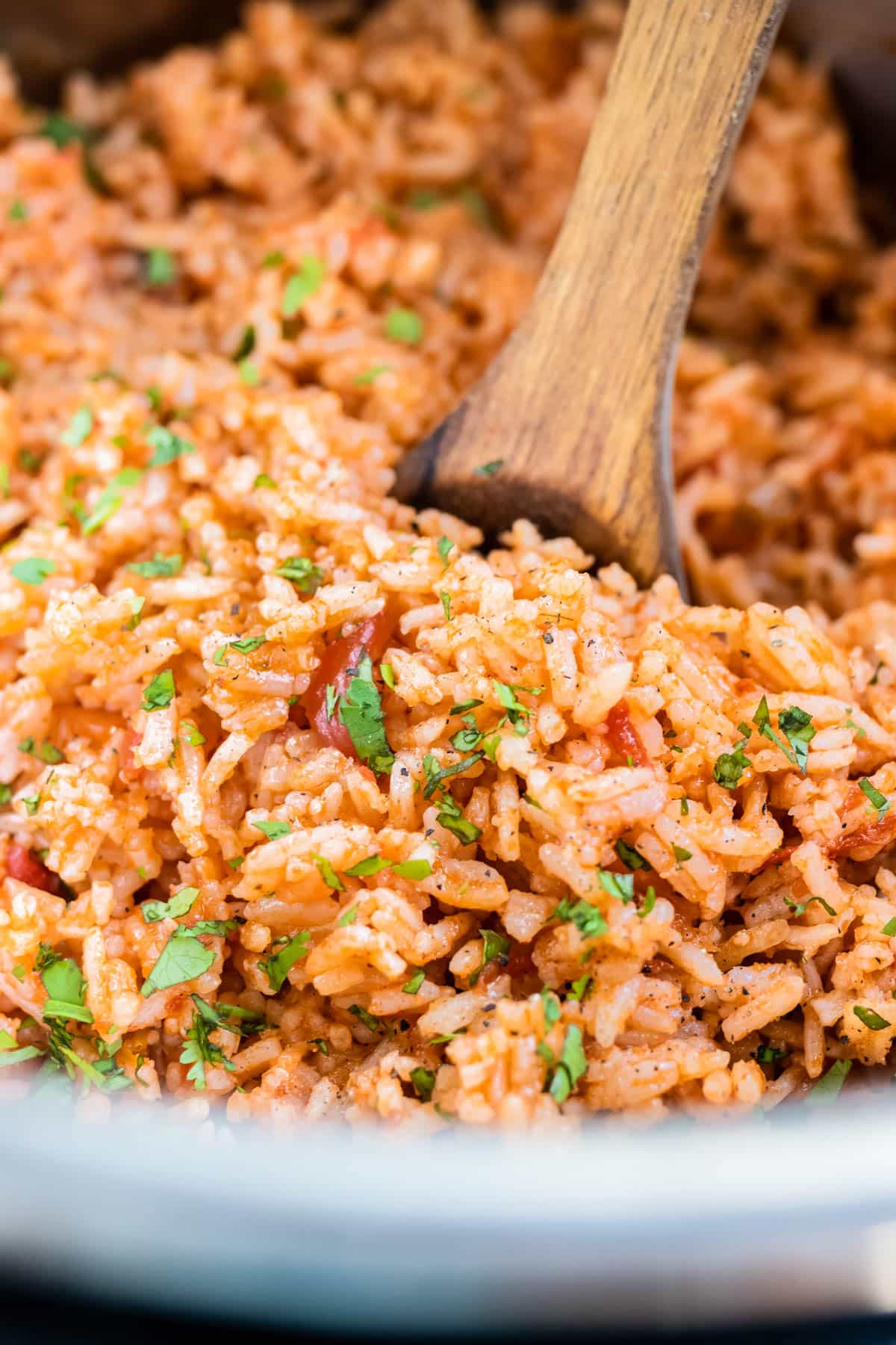 A wooden spoon is in an Instant Pot with a homemade Mexican Rice recipe.