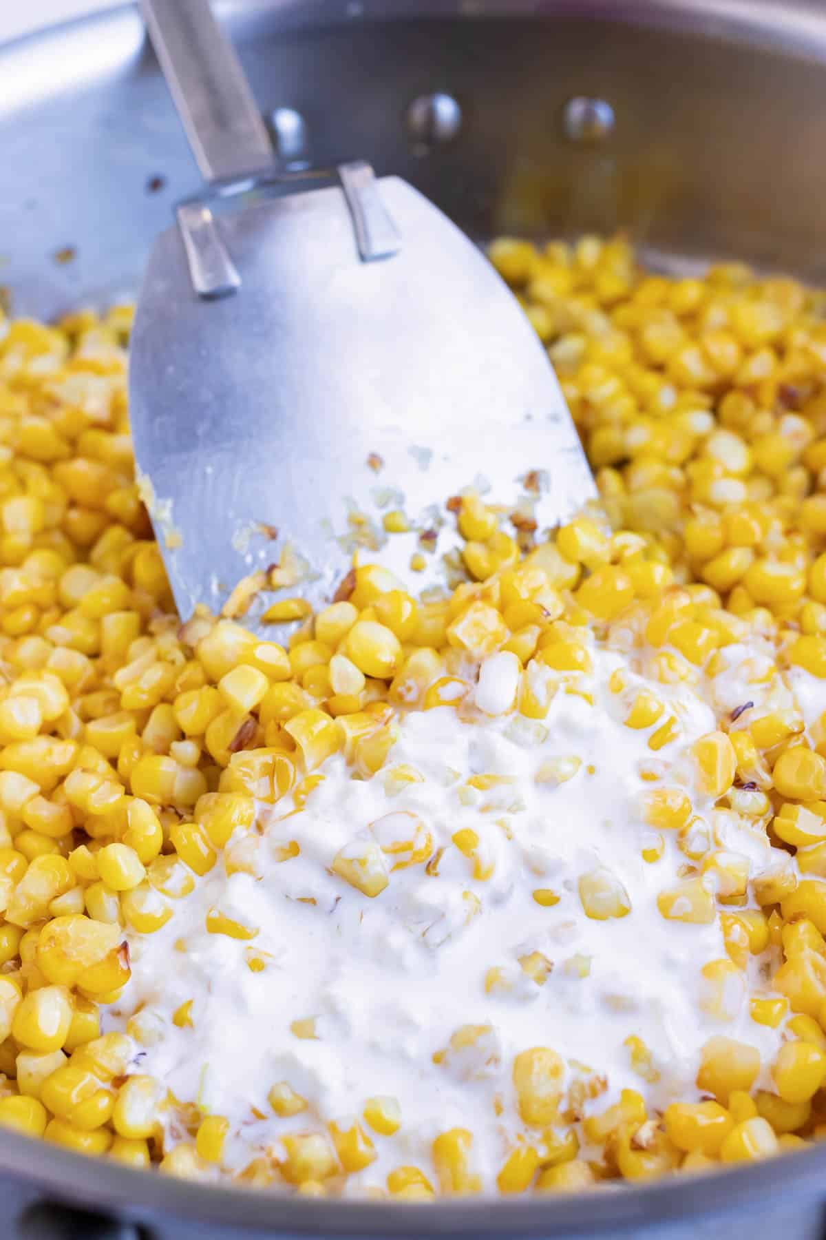 Sauce is added to the corn in the skillet.