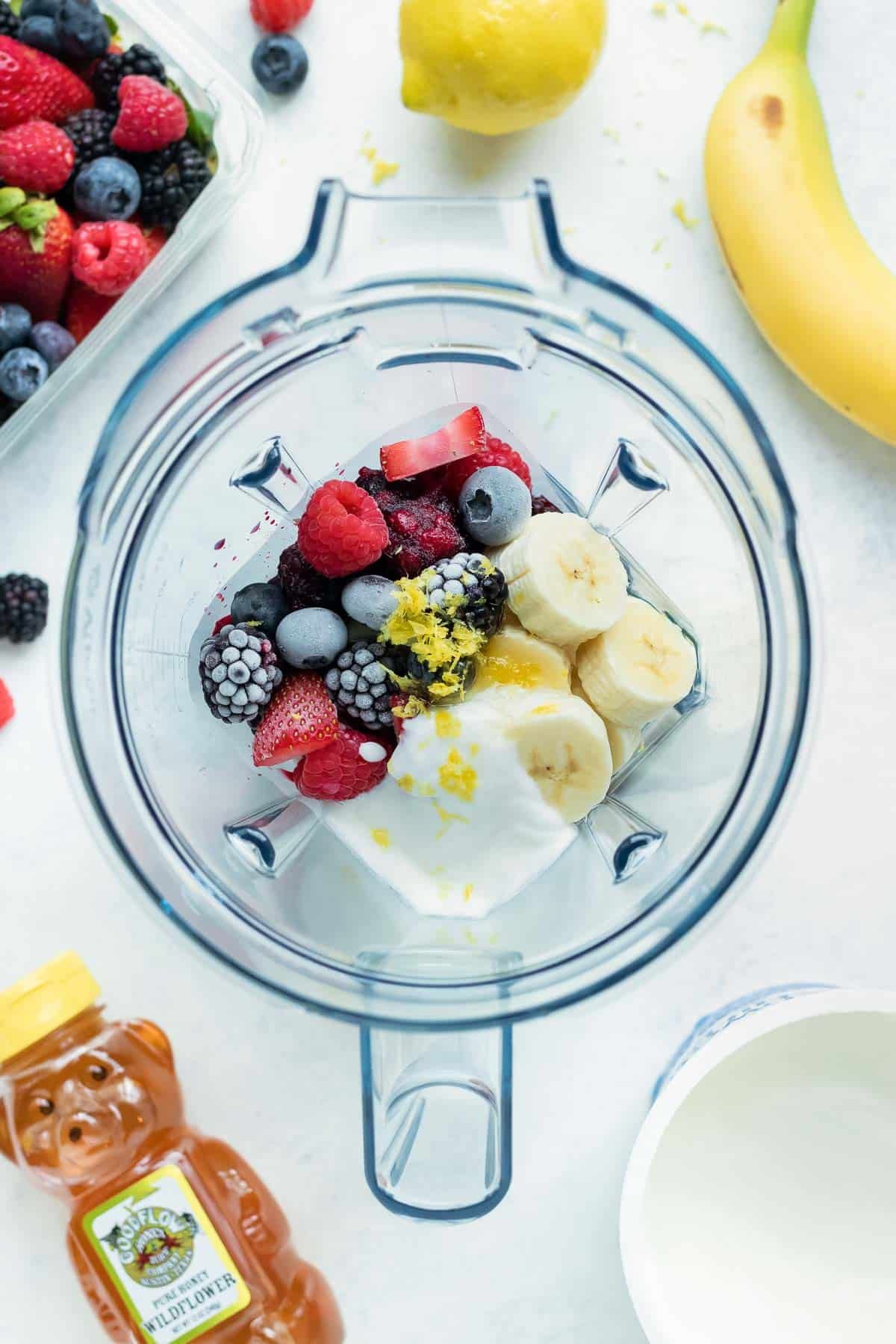 Frozen berries and other ingredients are added to a high speed blender for a fruit smoothie recipe.