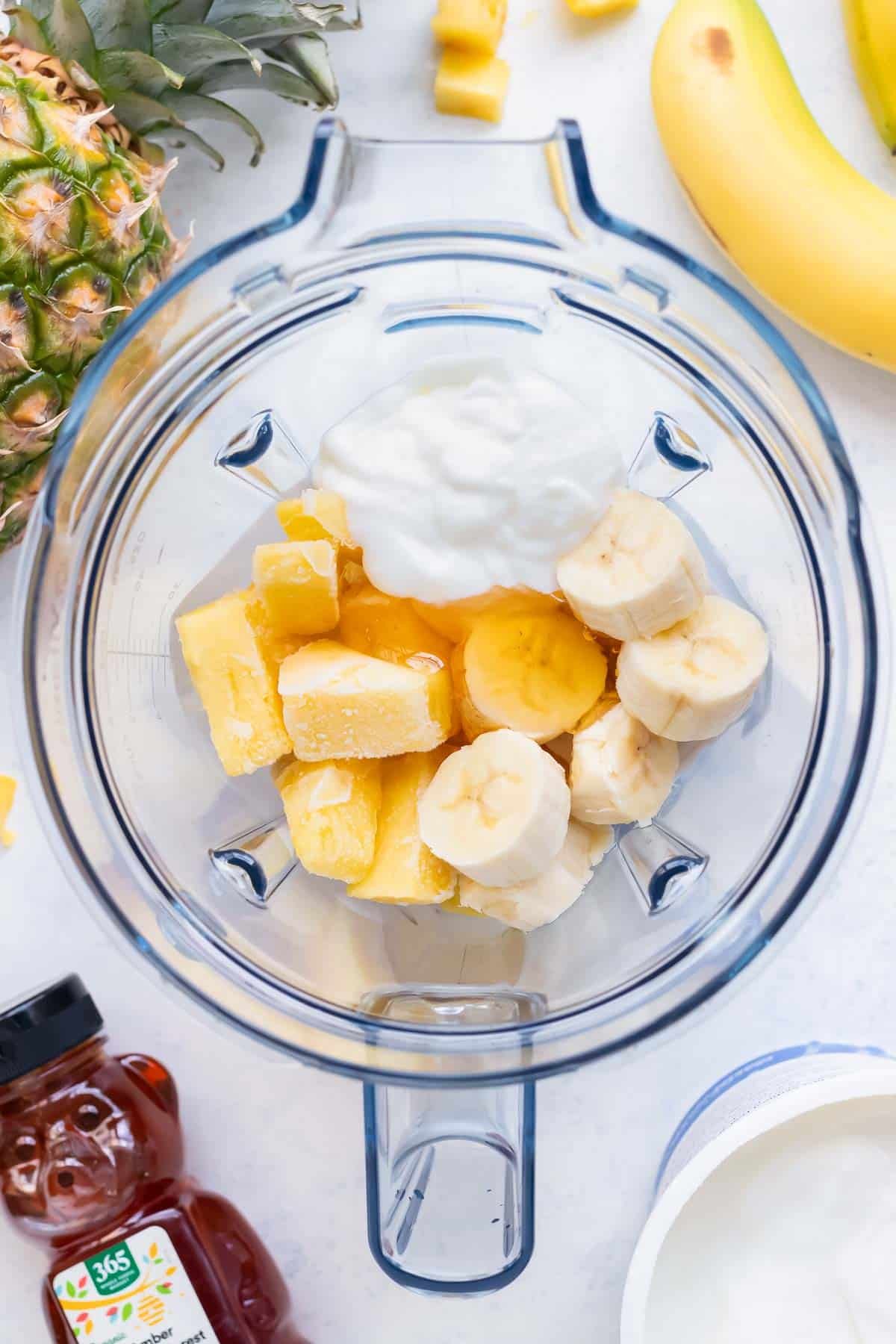 Ingredients for this pineapple coconut smoothie are combined in a blender.