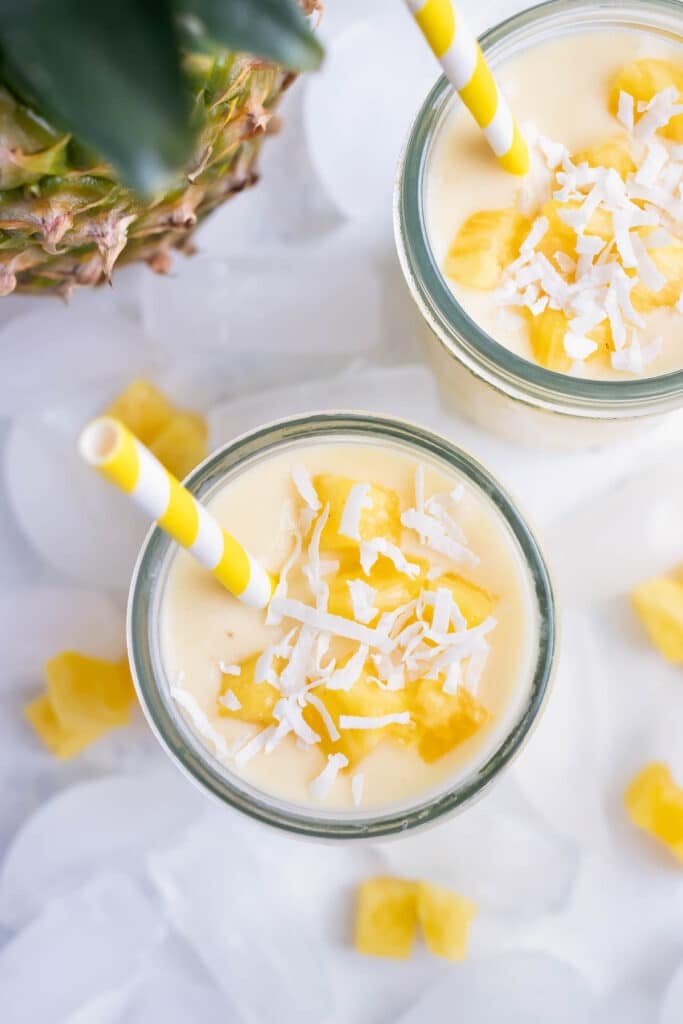 Creamy Pineapple and coconut smoothies are enjoyed with a straw from a mason jar.