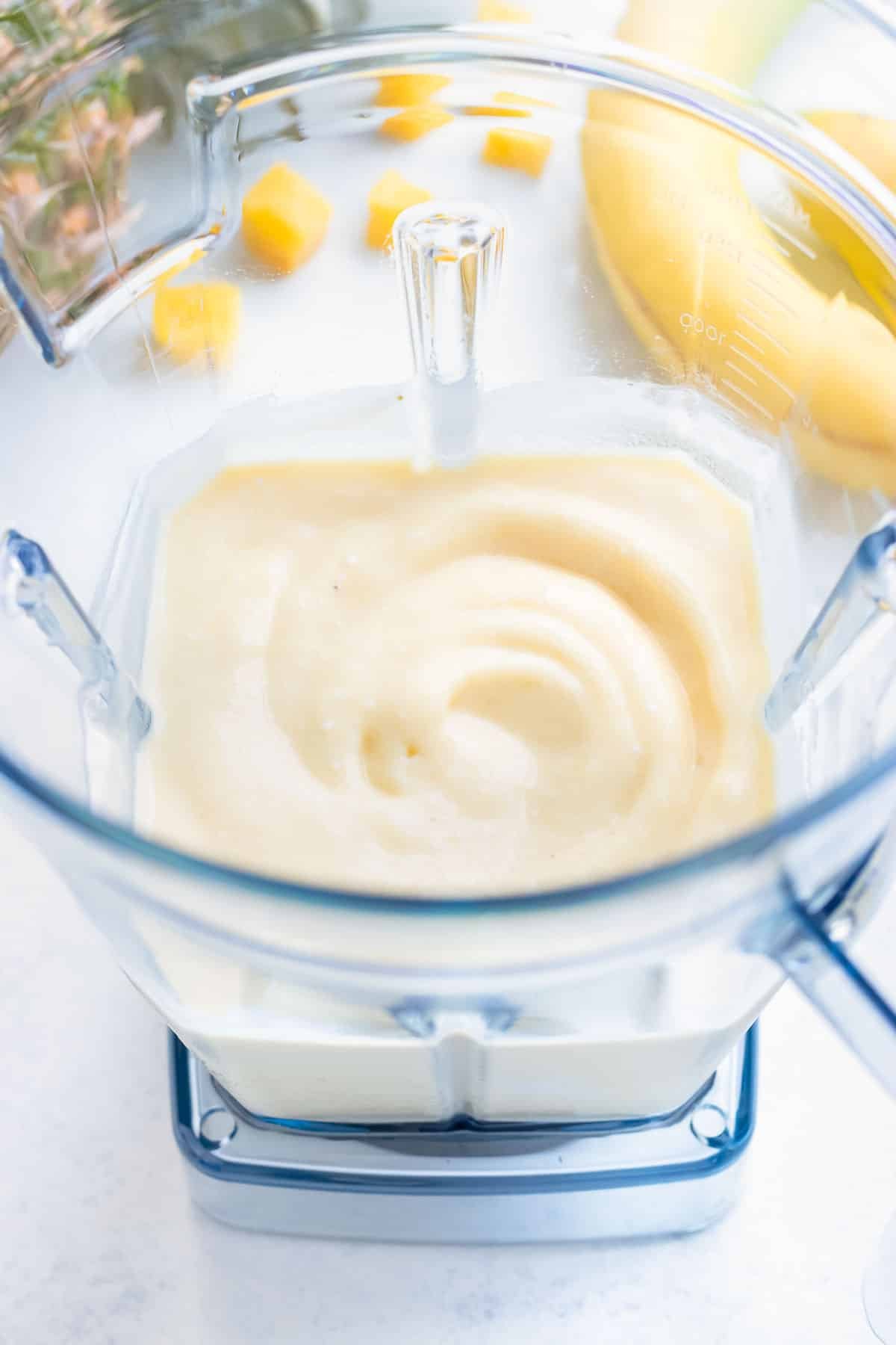 A creamy fruit smoothie is made in a blender.