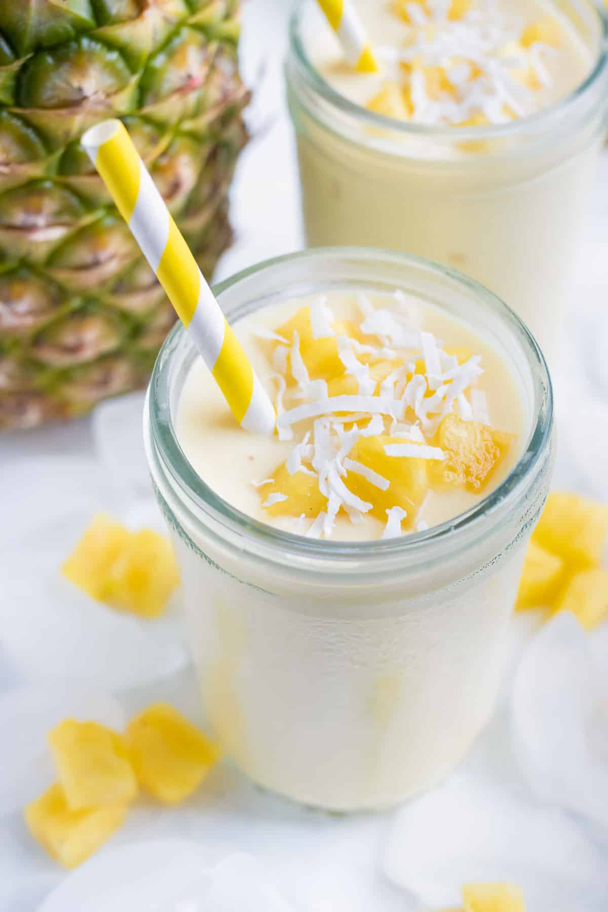 Pineapple smoothie is topped with cubed pineapple and shredded coconut.