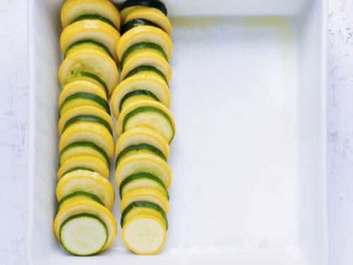 Yellow squash and zucchini are layered into a baking dish.