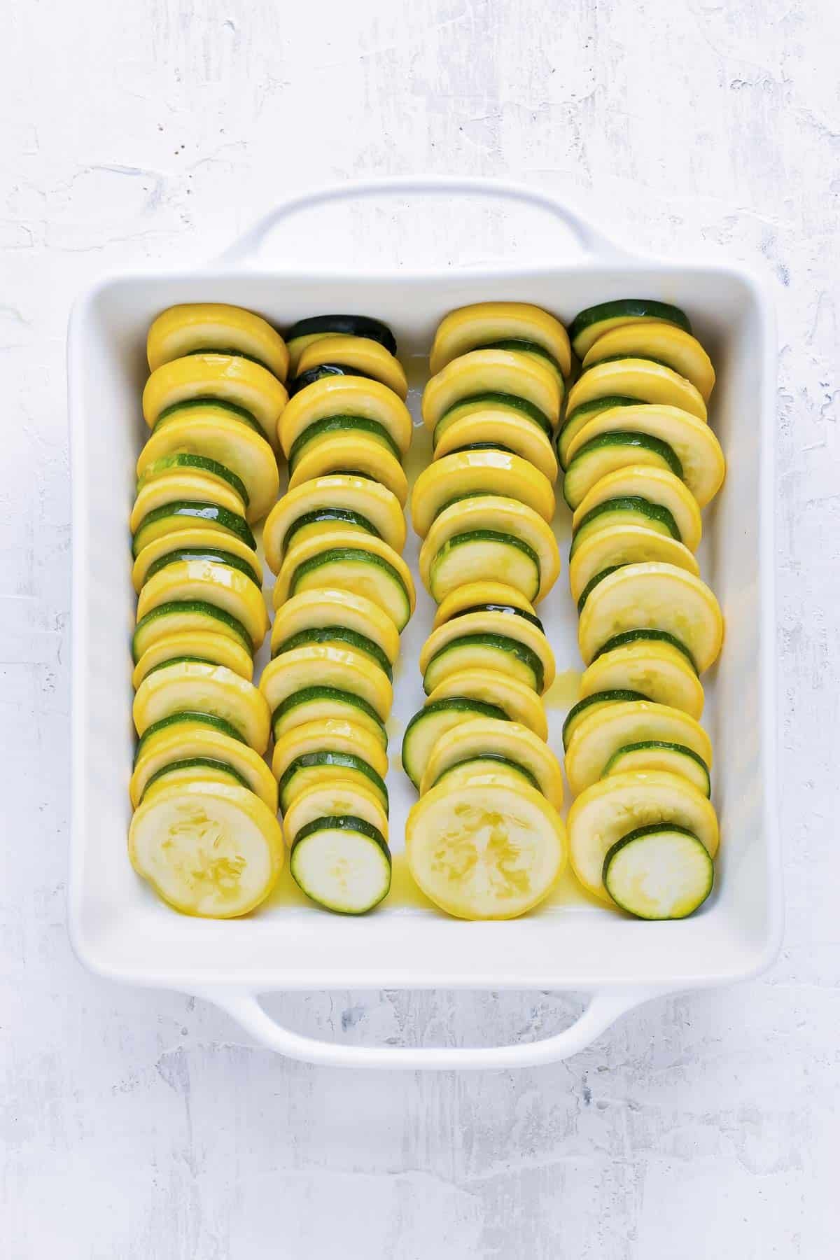 Yellow squash and zucchini are layered into a baking dish.