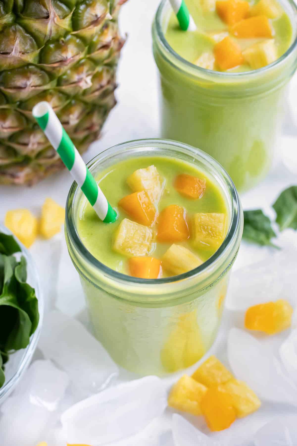 Tropical green smoothies are served in a glass with a straw for breakfast.