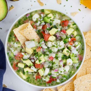 An appetizer bowl full of a fish and avocado Mexican dip recipe surrounded by tortilla chips.