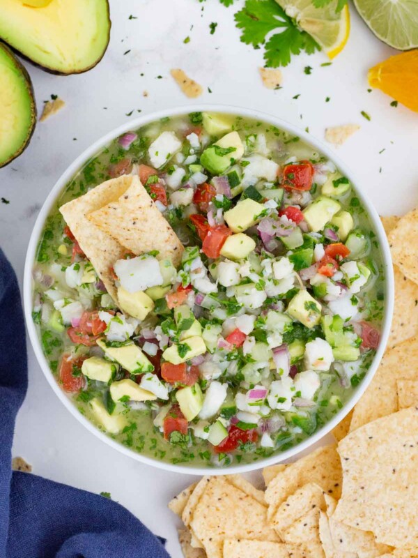 An appetizer bowl full of a fish and avocado Mexican dip recipe surrounded by tortilla chips.