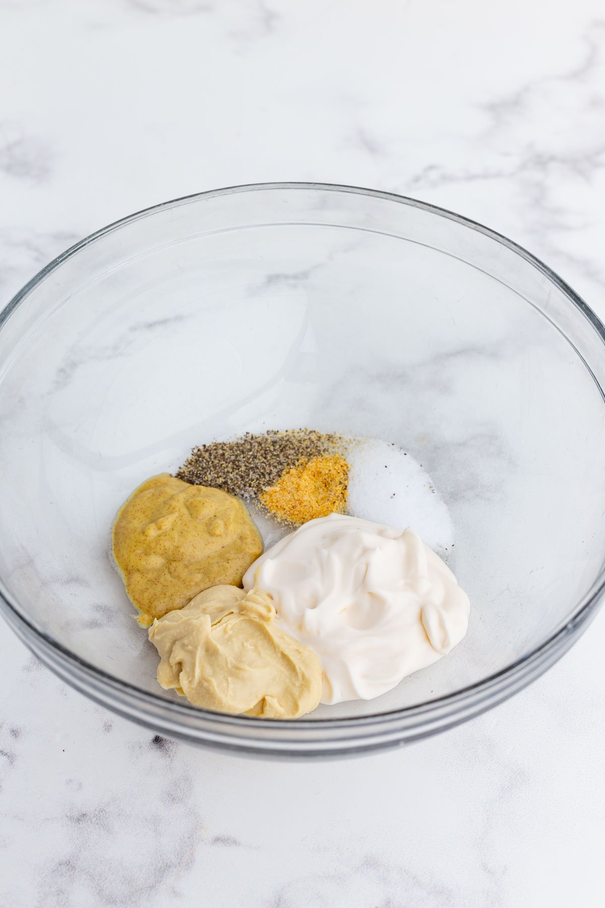 The sauce ingredients are added to a glass bowl.