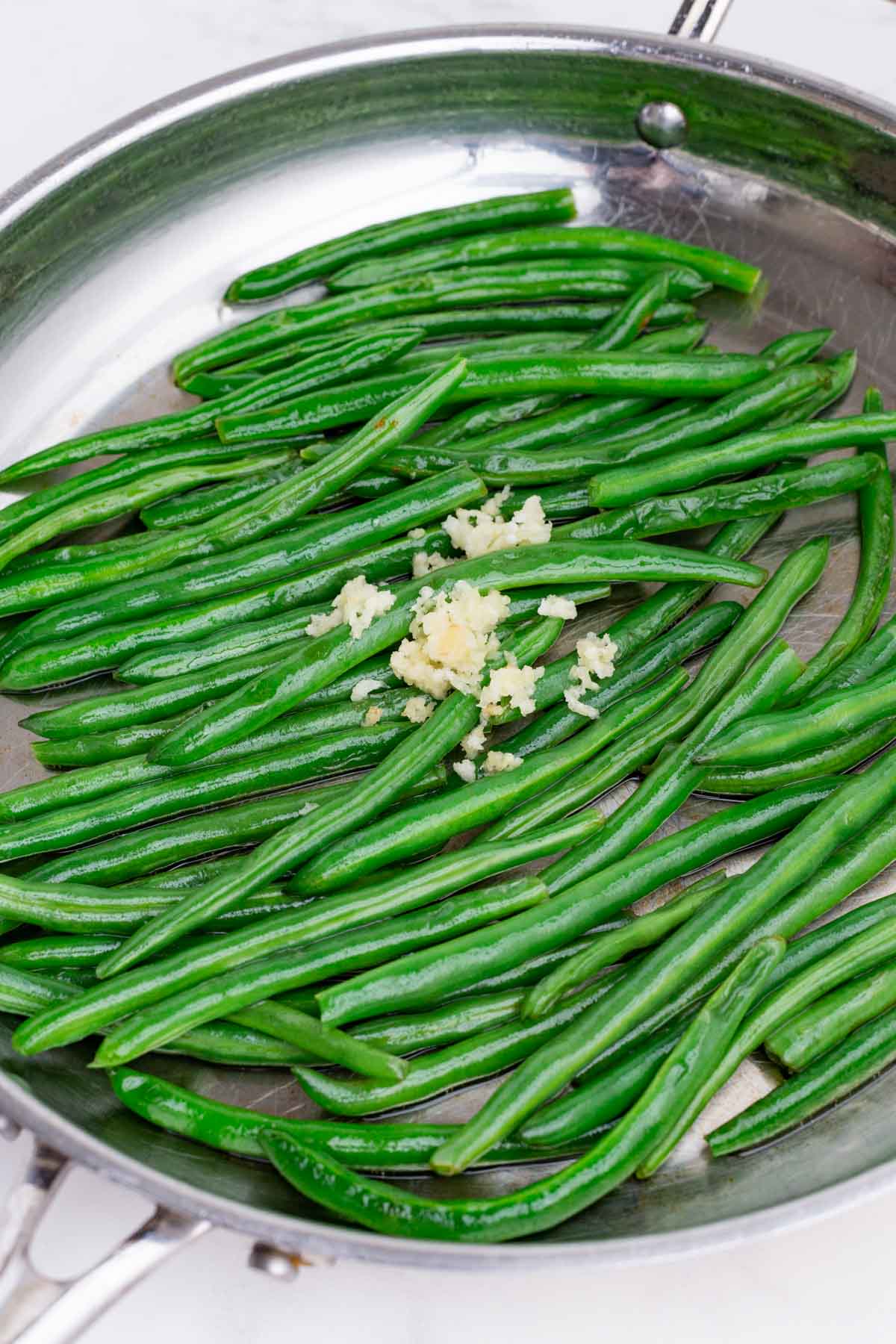 Garlic is added to the cooked green beans.