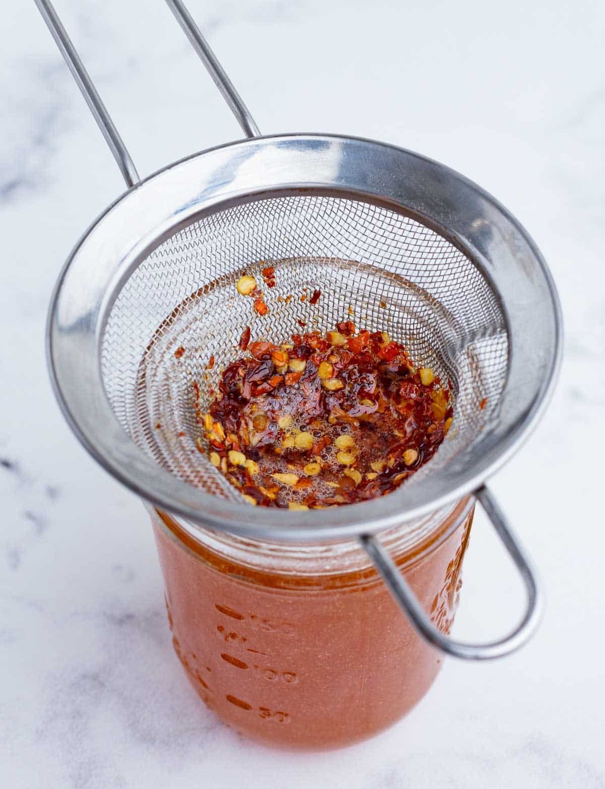 Hot honey is strained to remove the pepper flakes.