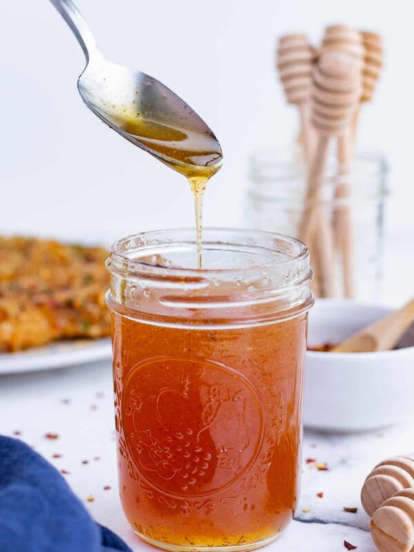 A spoon drizzles some hot honey over the jar.