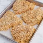 Breaded chicken is placed on a pan to bake.