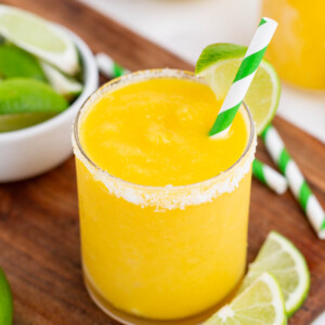 A frozen mango margarita is topped with a lime wedge.