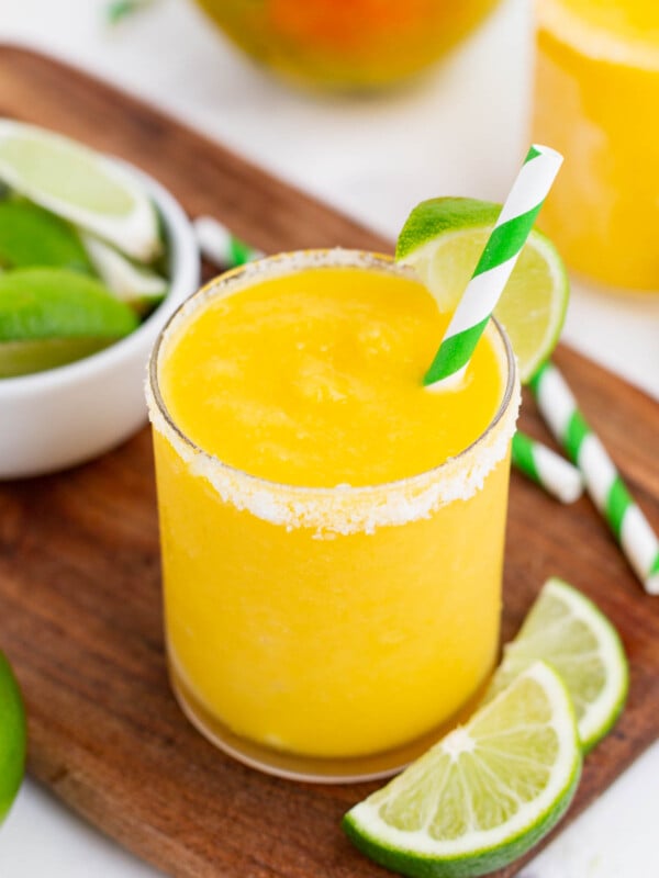 A frozen mango margarita is topped with a lime wedge.