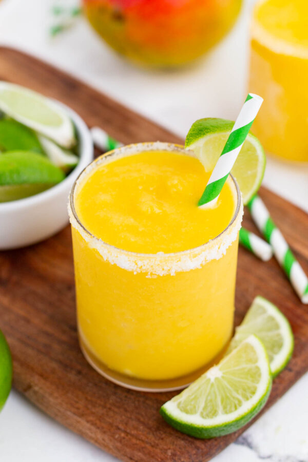 A frozen mango margarita is topped with a lime wedge.
