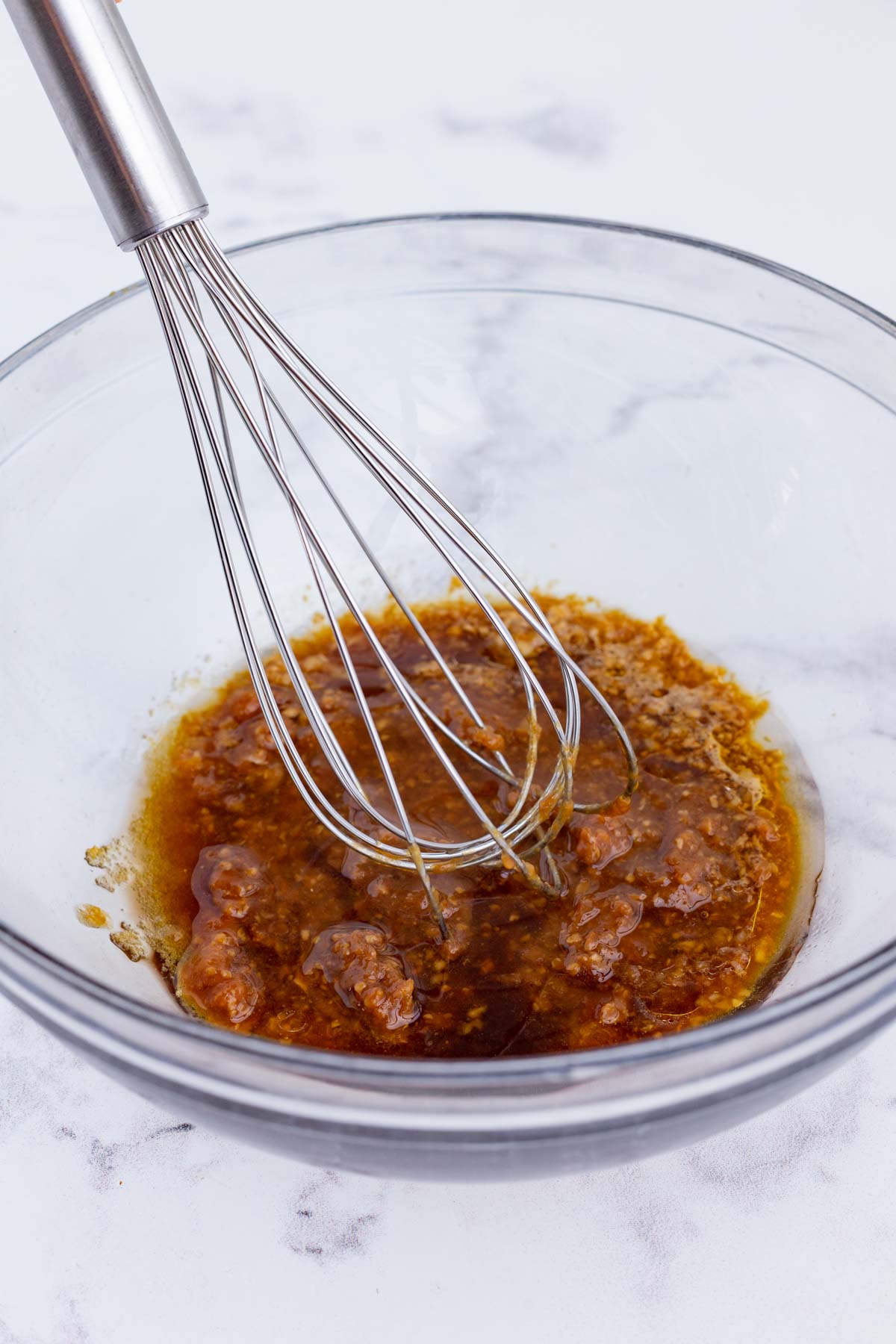 A whisk stirs the sauce ingredients.