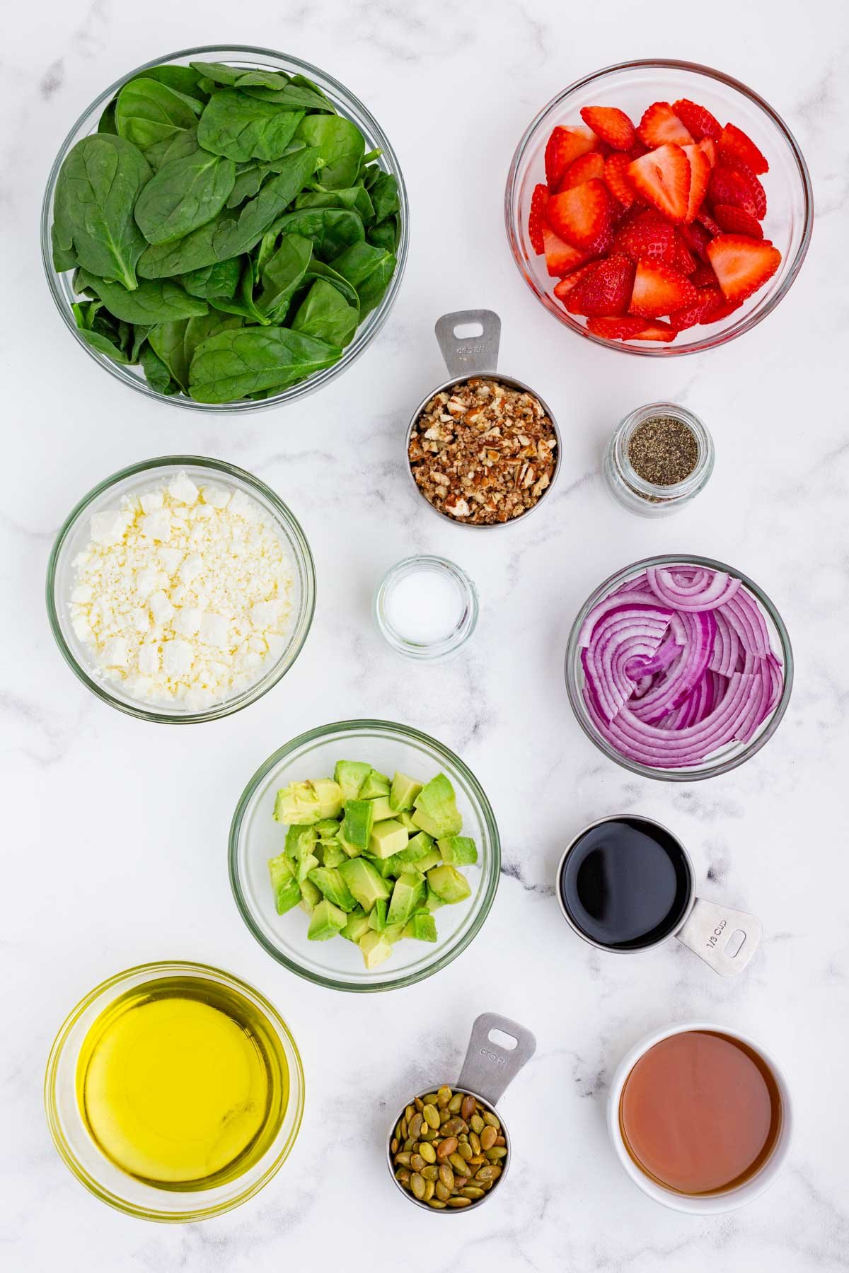 Spinach, strawberries, feta cheese, pecans, red onion, avocado, and balsamic vinaigrette are the ingredients for this salad.