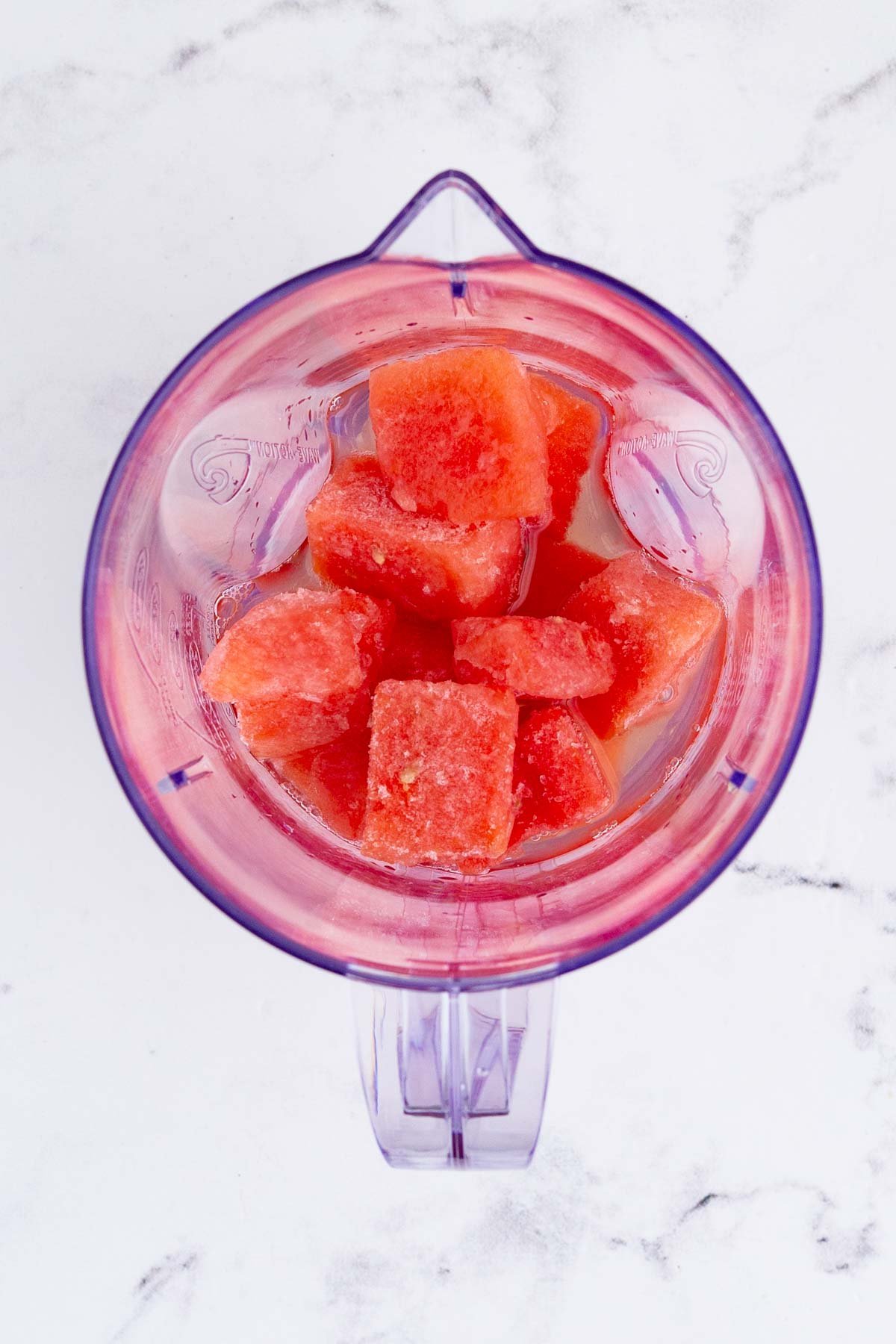 Frozen watermelon chunks and liquor are added to a blender.
