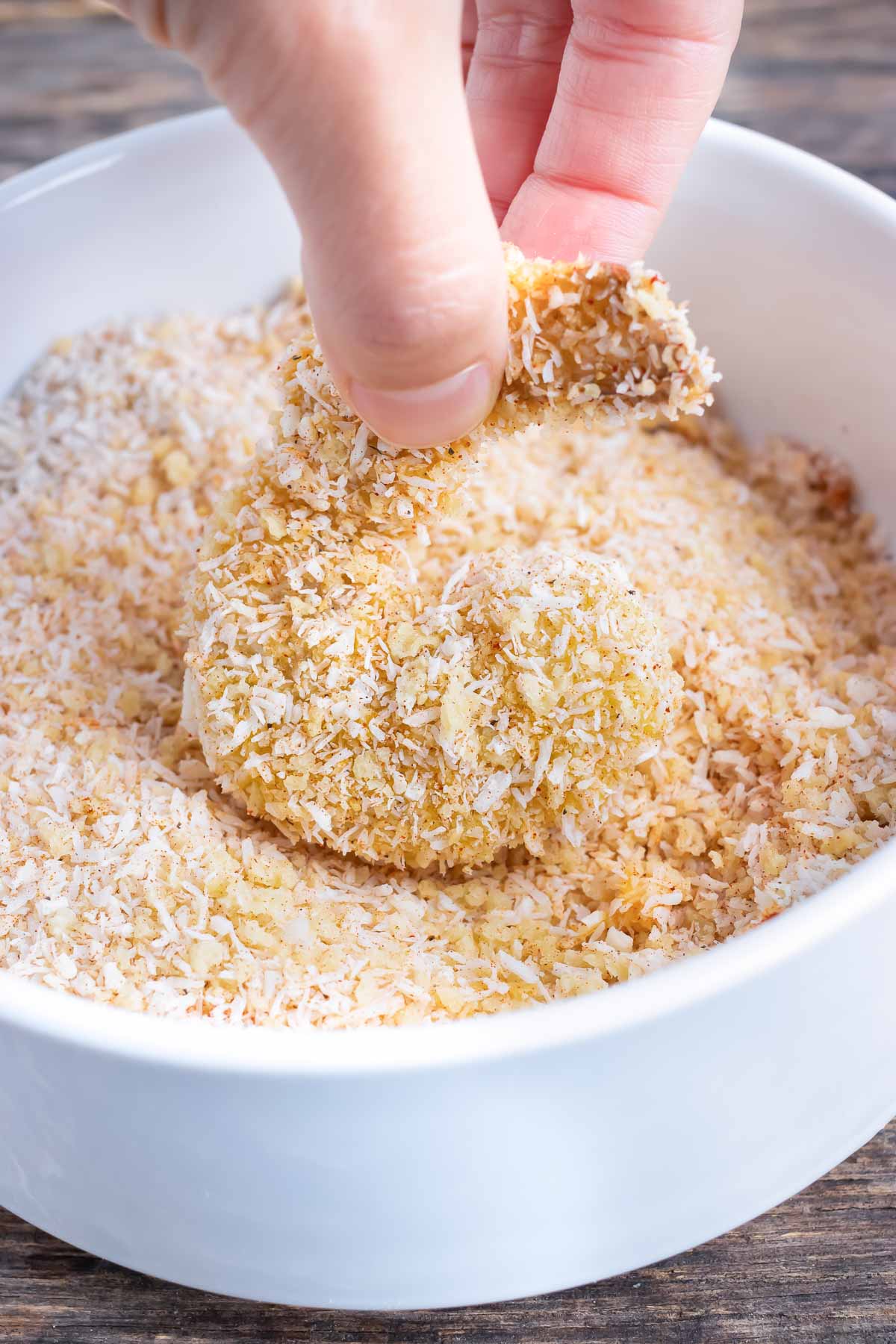 Floured shrimp is dipped into a breadcrumb mixture.