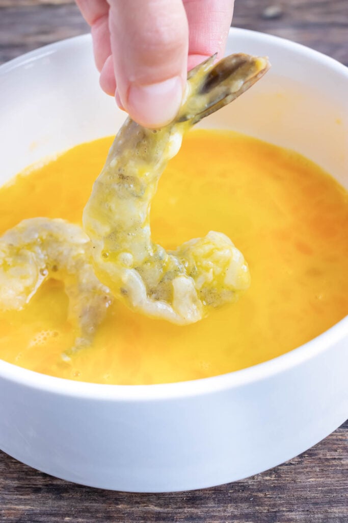 Floured shrimp is dipped into an egg mixture.