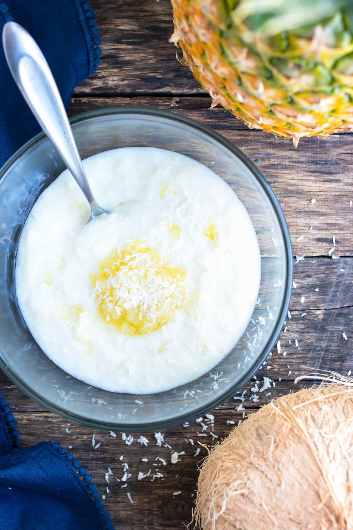 Fried coconut shrimp being dipped into a piña colada sauce.