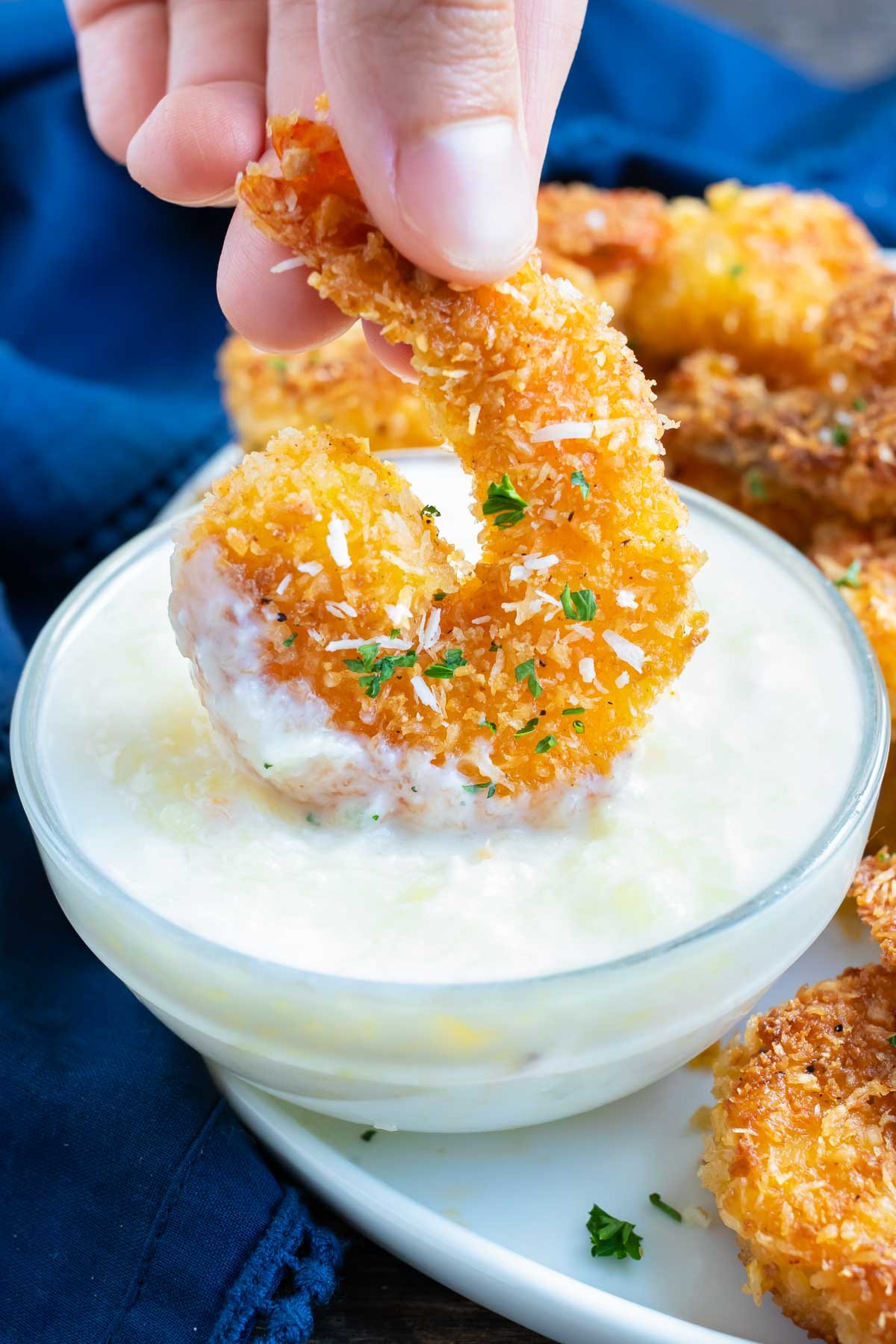 Fried coconut shrimp being dipped into a piña colada sauce.