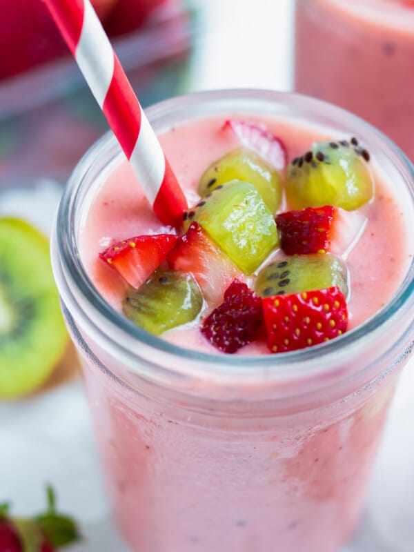 Fresh kiwis and strawberries are placed on the top of a smoothie.