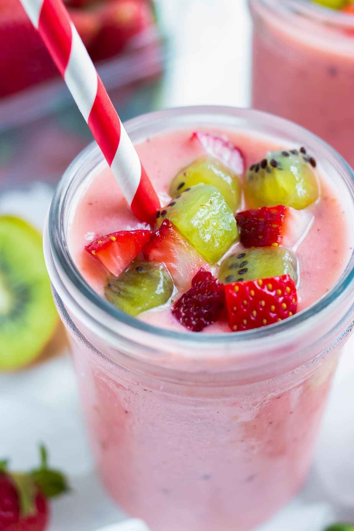 Strawberry Kiwi Smoothie RECIPE served in a mason jar and topped with strawberries and kiwis.