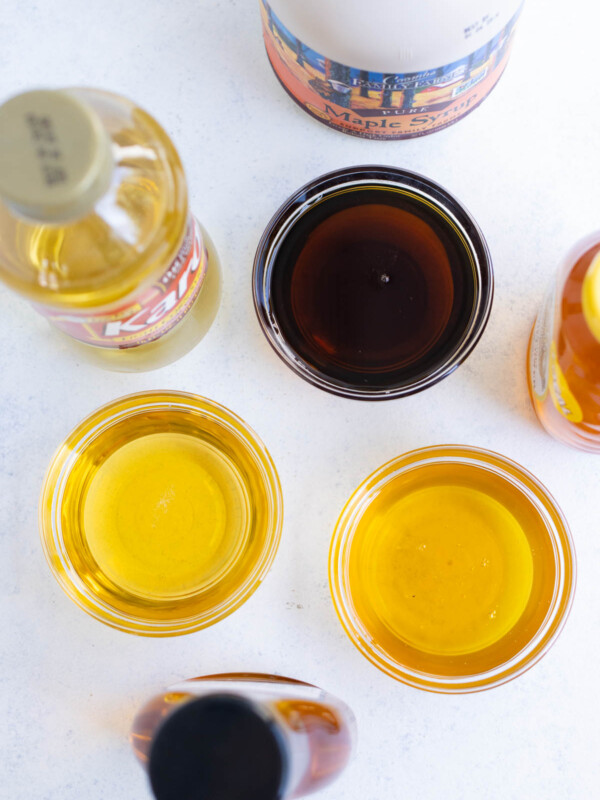 Top view of maple syrup, agave nectar, and honey poured in clear glass bowls.