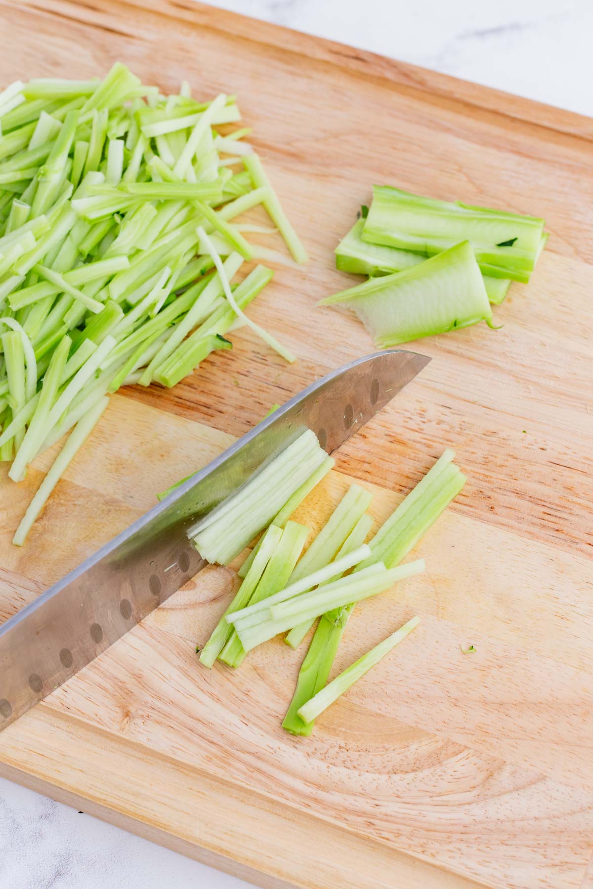 A knife julienne cuts broccoli stalks.