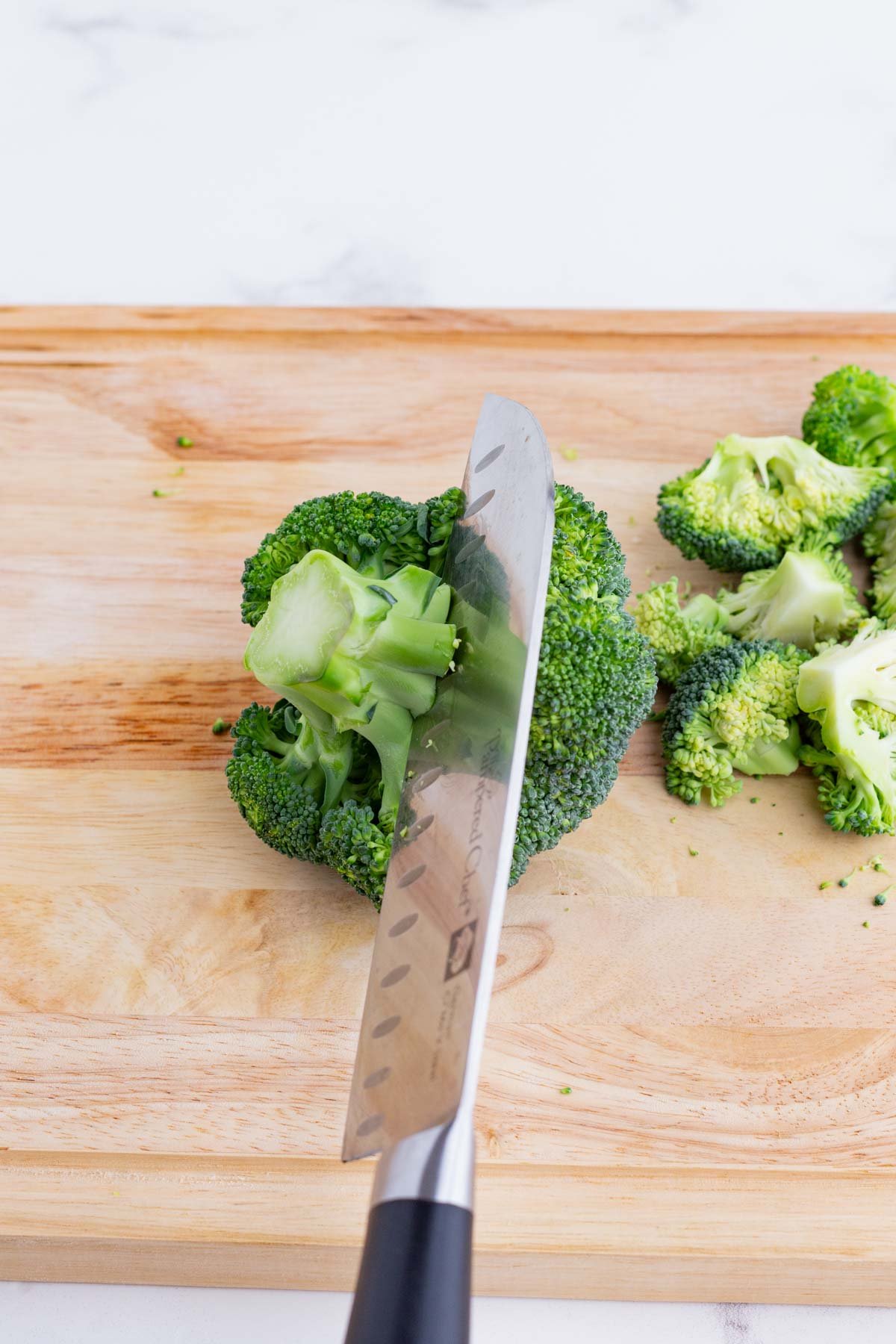 A knife cuts up broccoli florets.