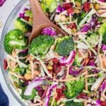 A wooden spoon is used to serve homemade broccoli slaw.