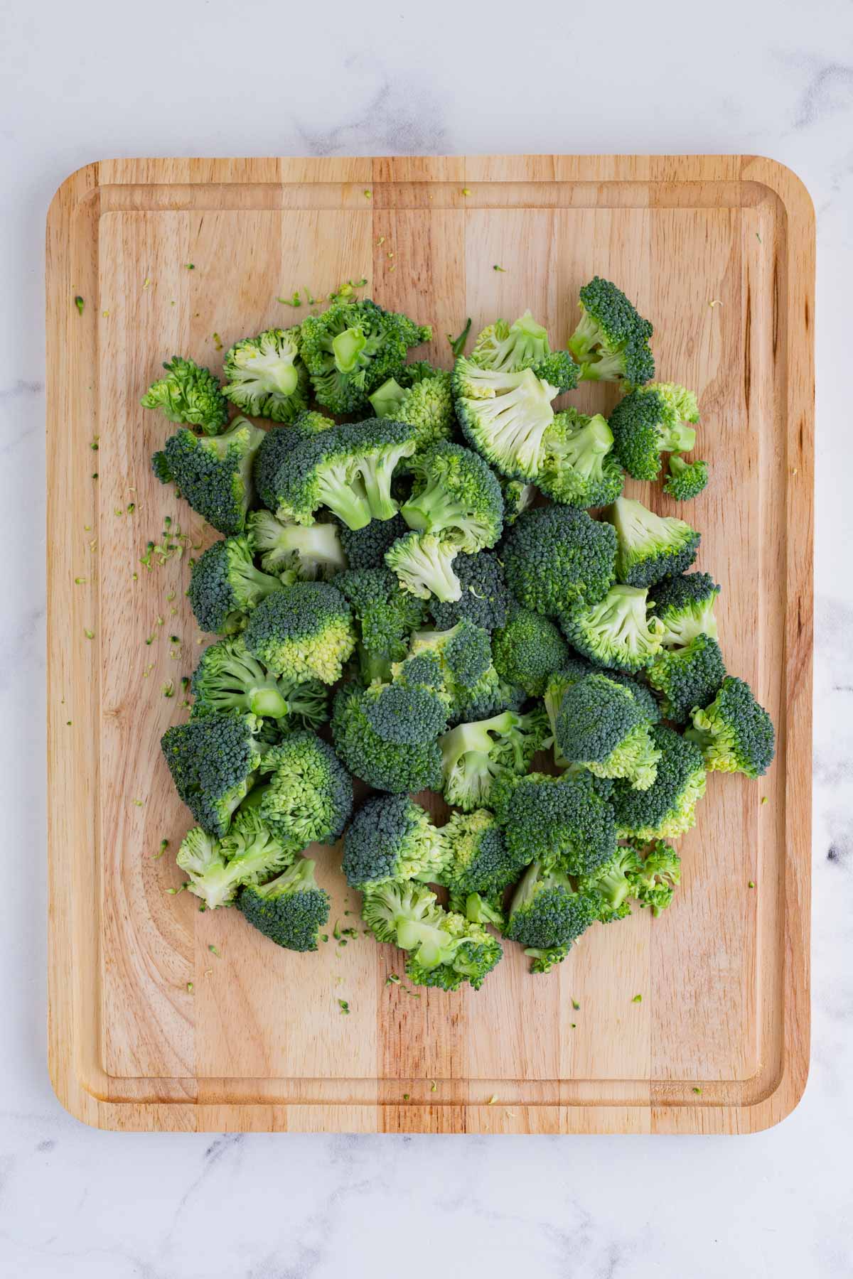 A knife cuts up broccoli florets.