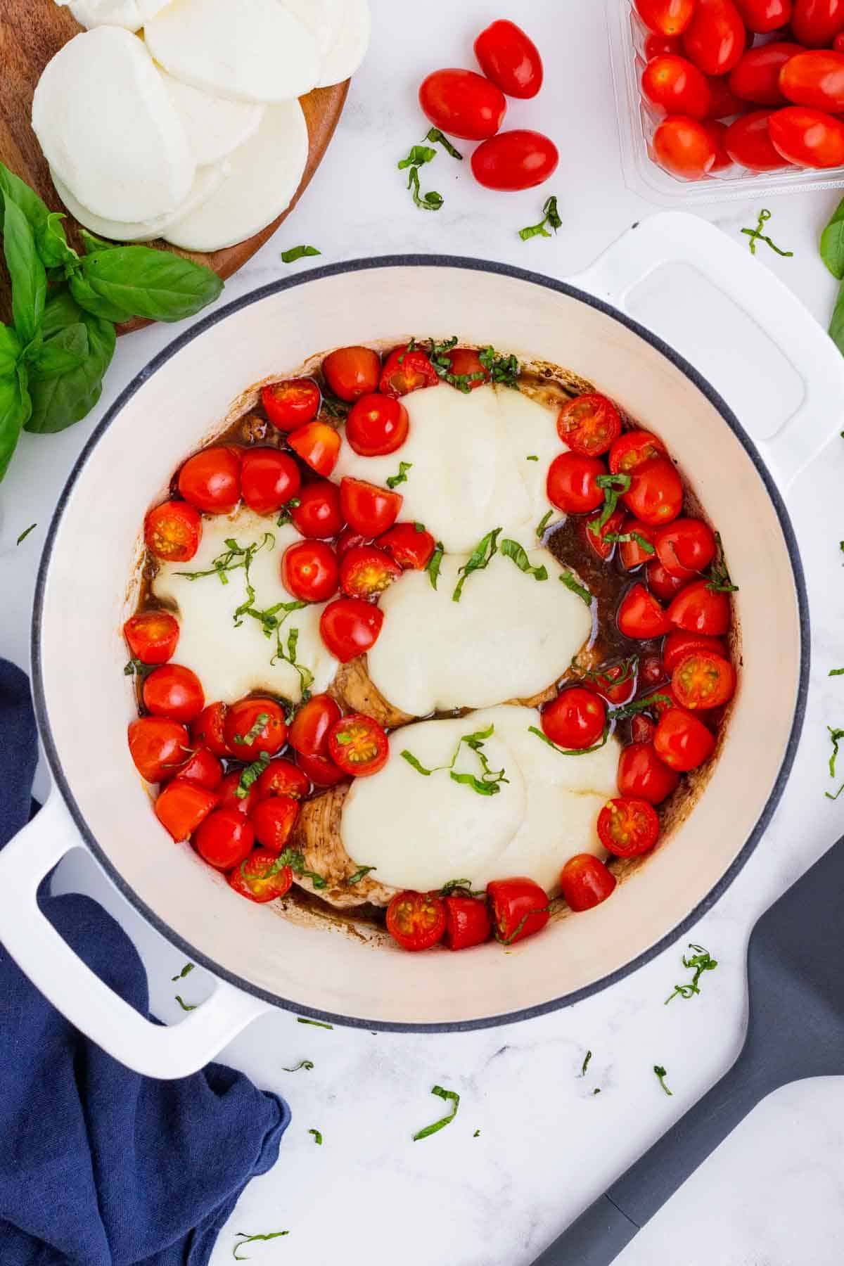 An overhead shot of caprese chicken in a skillet.
